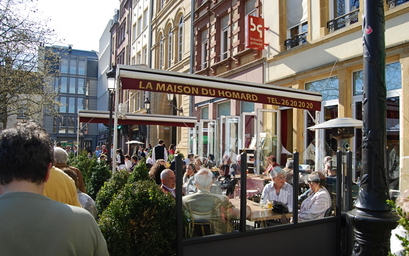 10 - La Maison du Homard, a restaurant featuring outdoor seating under a branded awning on a busy street